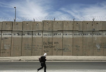 Një vajzë palestineze ecën përpara një pjesë të barrierës izraelite në al-Ram në Bregun Perëndimor në periferi të Jeruzalemit.